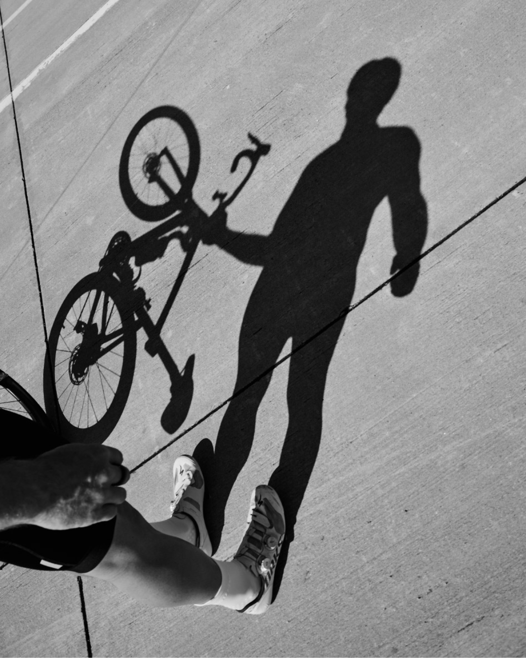 shadow of athlete holding bike on side and wearing courier HiFi white performance socks